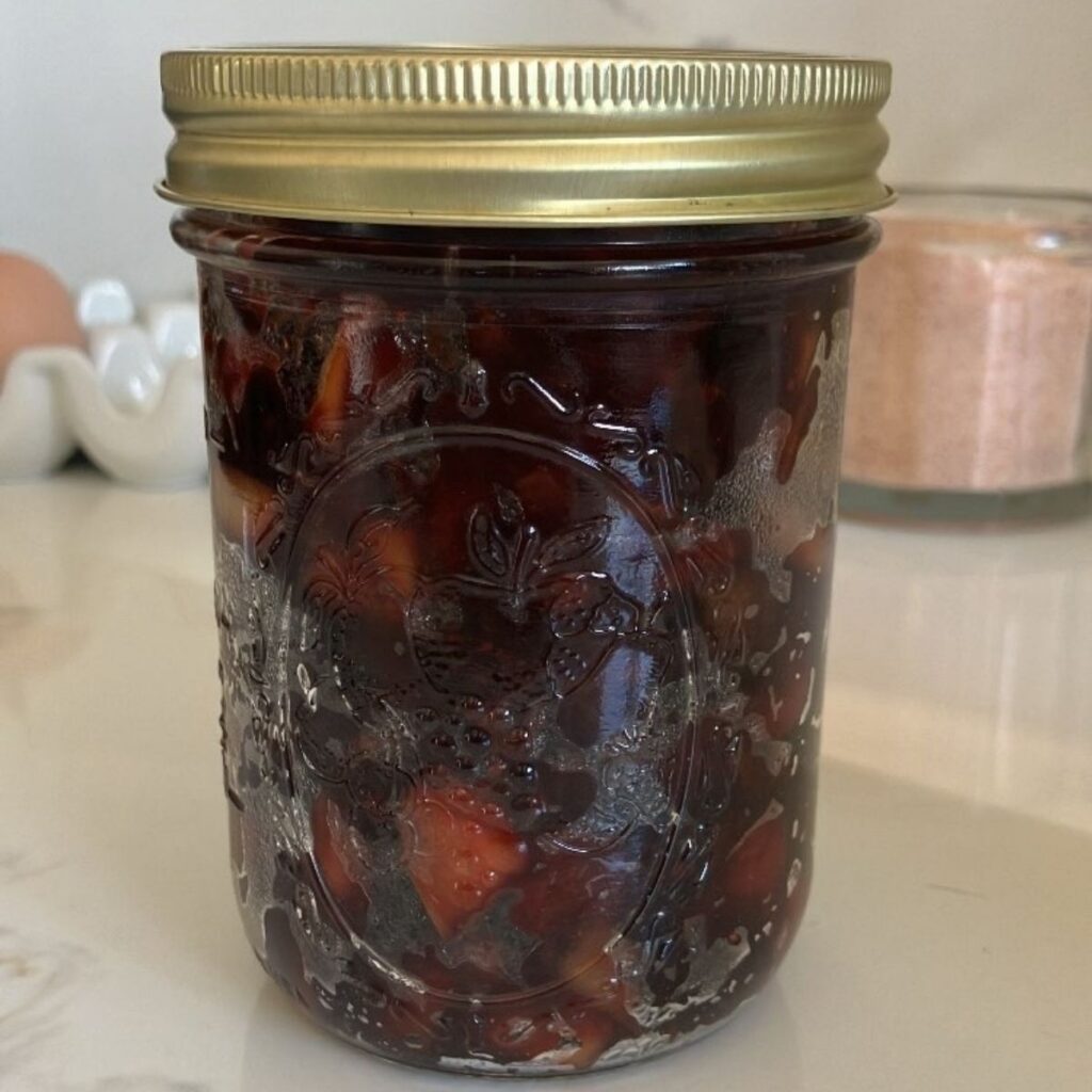 A mason jar of homemade cranberry sauce with a gold lid.