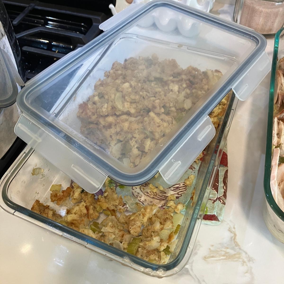 A glass baking dish of stuffing with a plastic lid sitting on top.