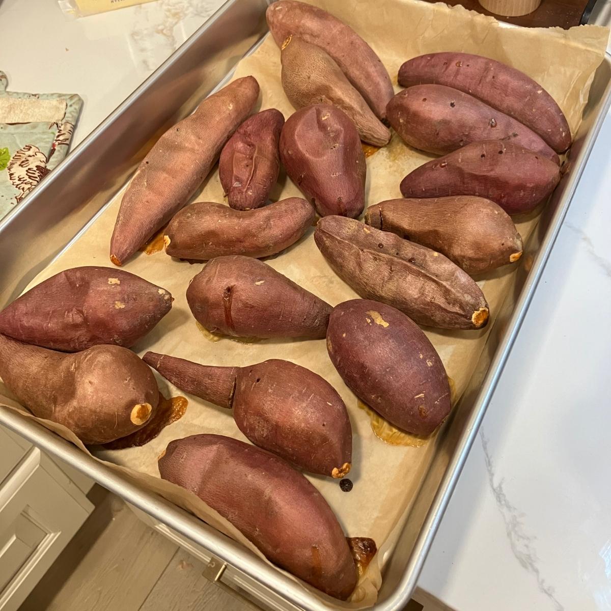 A baking sheet of roasted whole sweet potatoes.