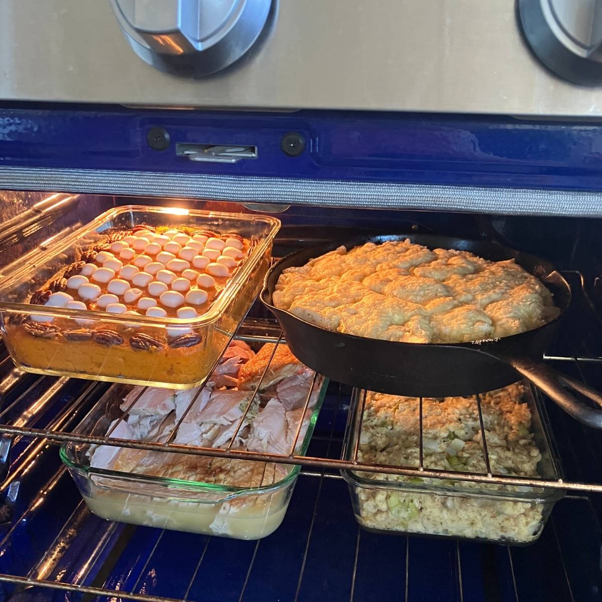 An oven door open with four casserole dishes inside being heated up.